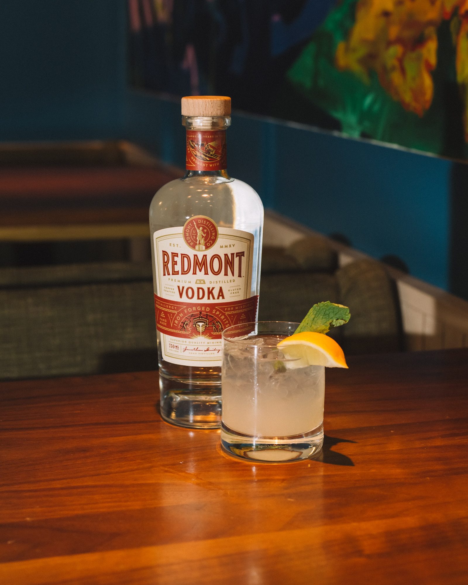 Redmont Vodka bottle beside a finished highball on a wooden table