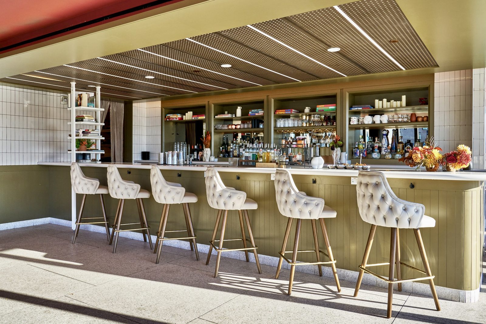 The rooftop bar at Hotel Indigo Williamsburg, stools set along the counter beneath a lit back bar
