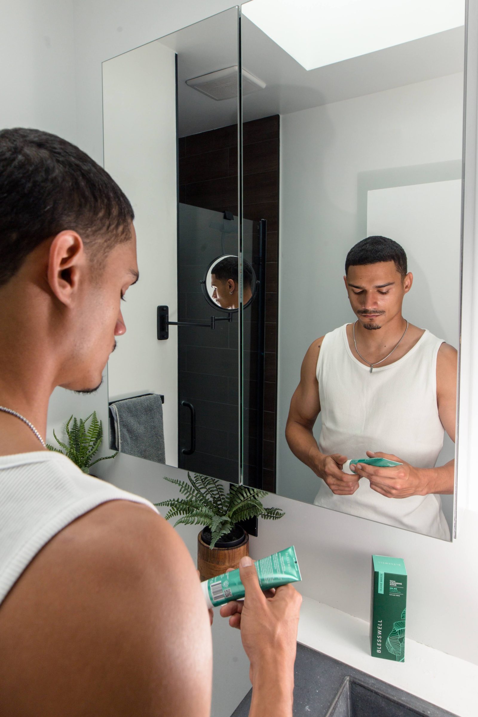 Man applying BLESSWELL cream at the mirror, product on the counter