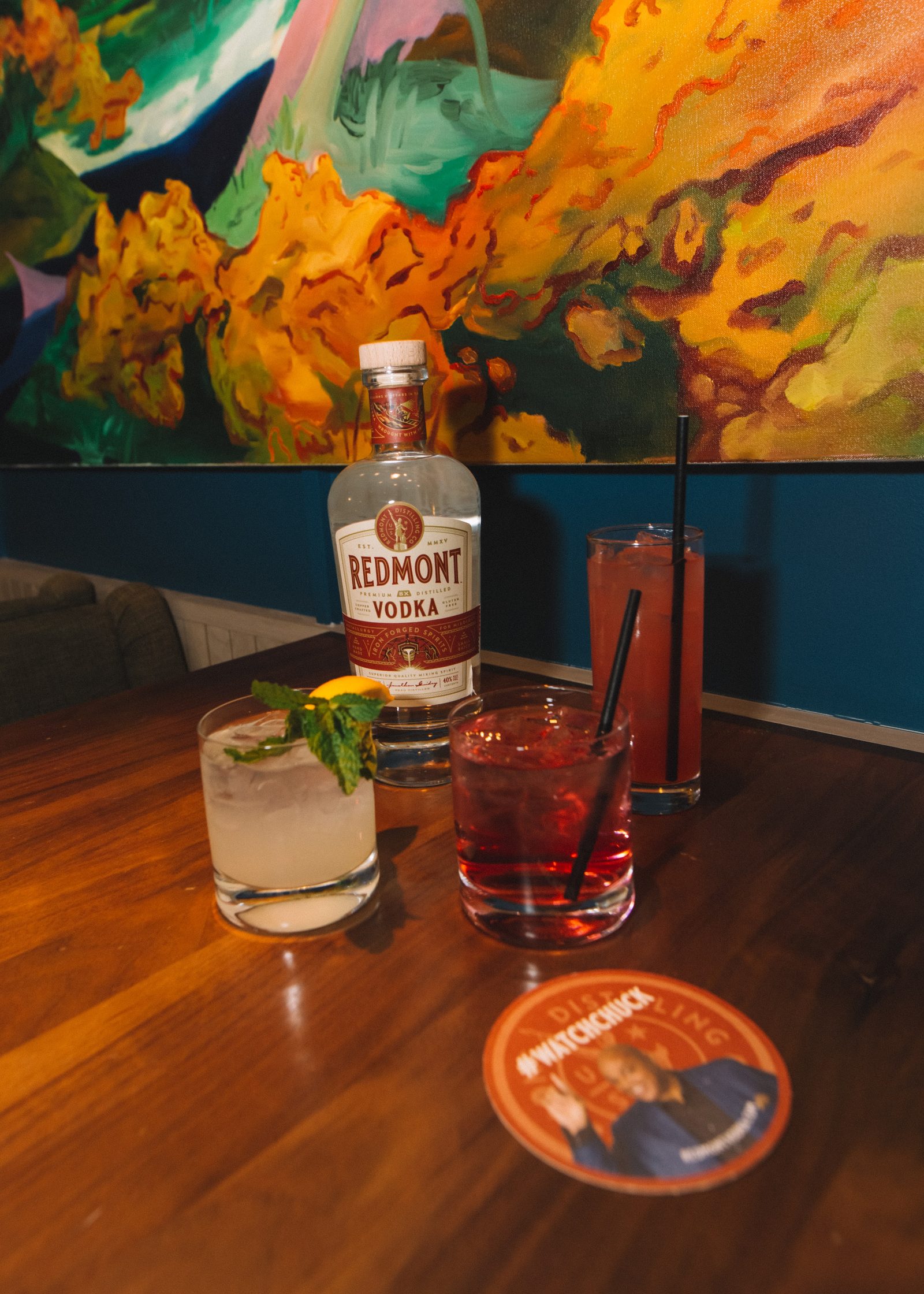 Two Redmont Vodka cocktails on a wooden table beneath a painted mural